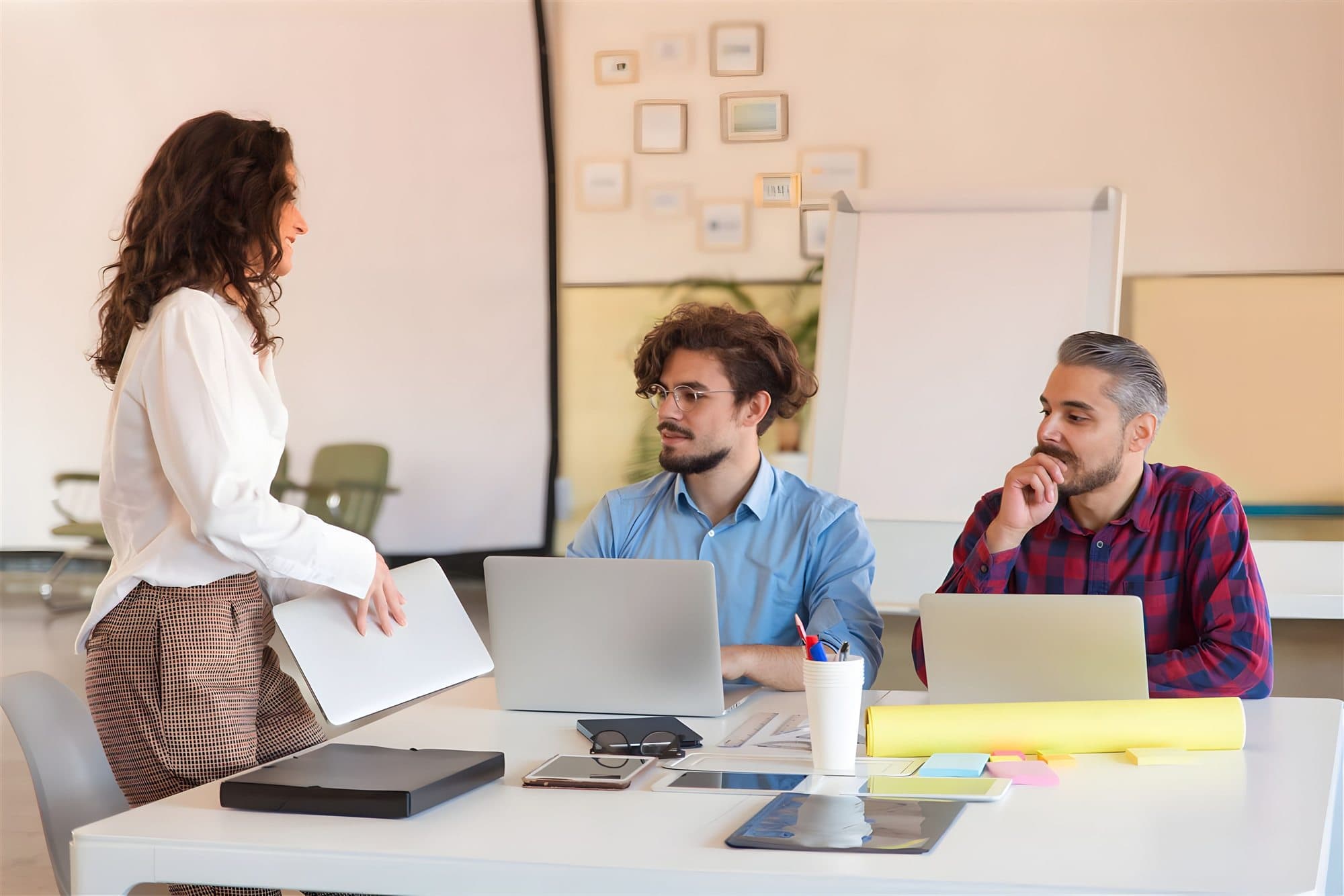 A leader standing at a desk, talking through next steps with two colleagues
